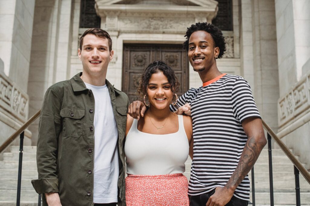 positive young multiracial students hugging on stairs of old university building