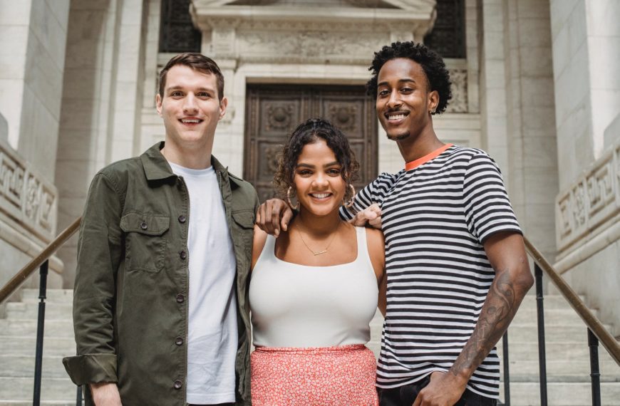 positive young multiracial students hugging on stairs of old university building