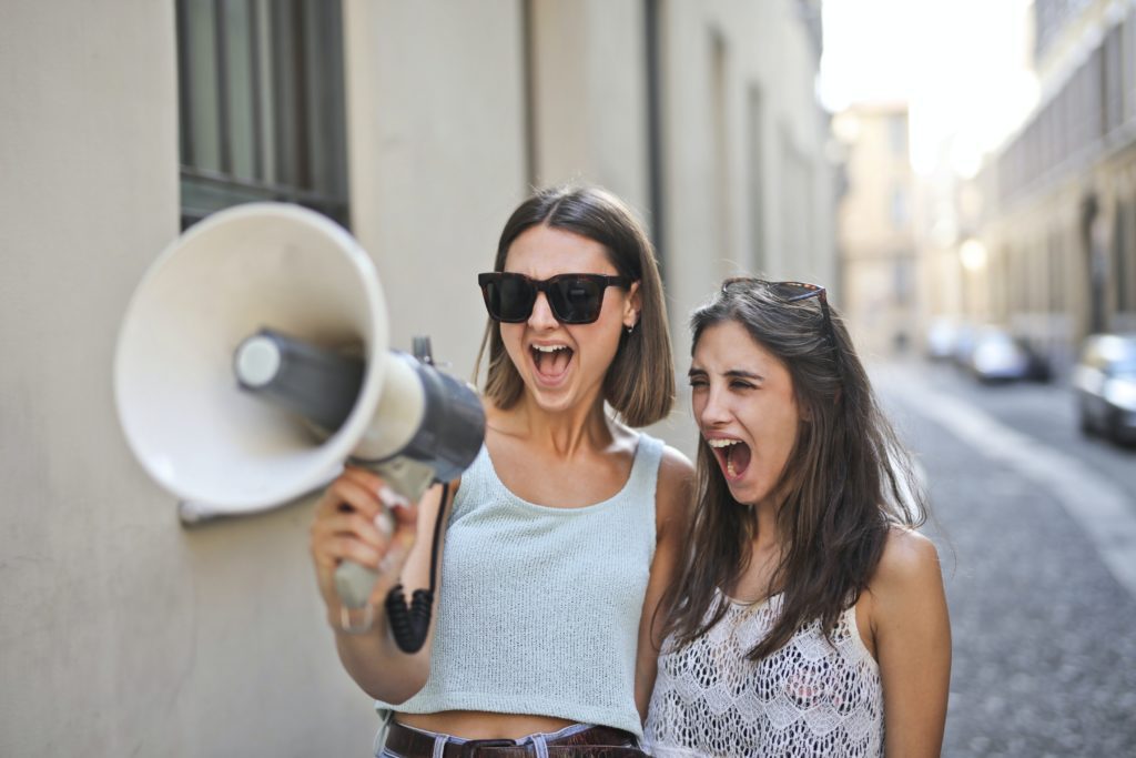 two girls shouting into a megaphone together