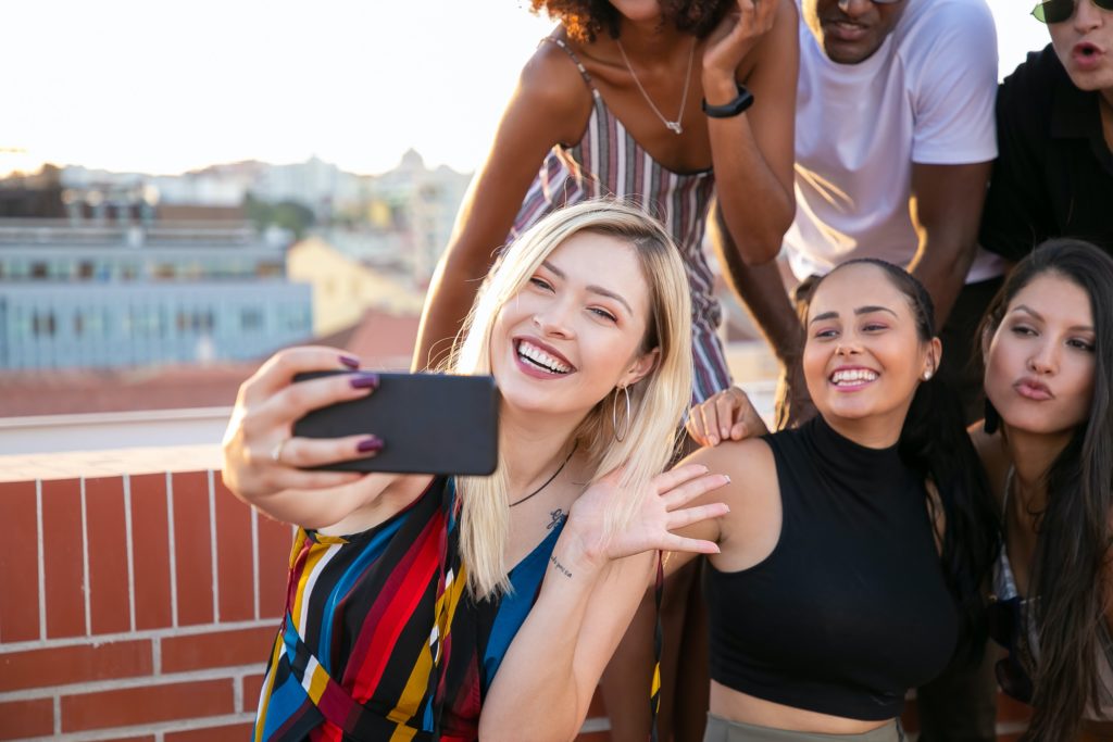 Influencer taking a selfie with friends on a rooftop for social media