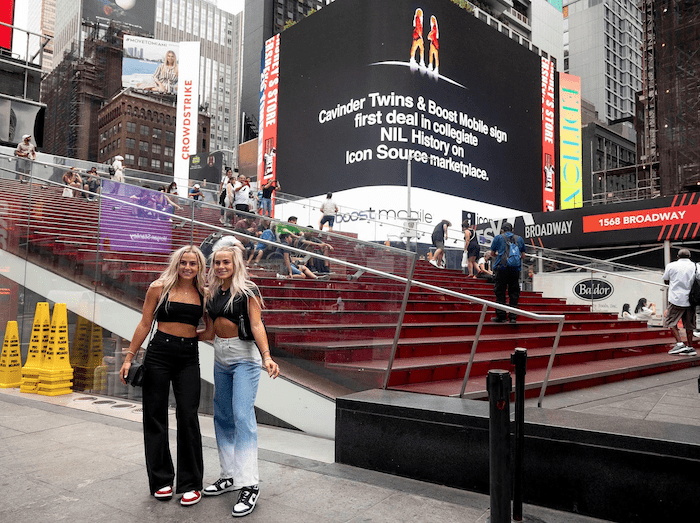 Cavinder twins in front of billboard announcing Boost Mobile sponsorship